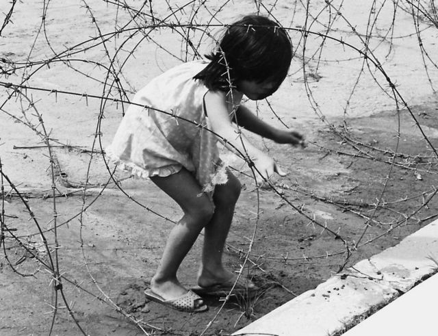 Una niña juega en un alambre de púas, en Vietnam.