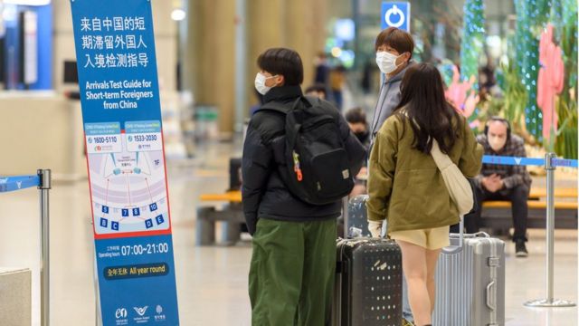 2023/01/02: Arriving travelers pass the information board of the COVID-19 inspection site at Incheon International Airport, west of Seoul.