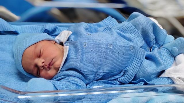 Bebê de Dandara na maternidade deitado e usando roupas azuis