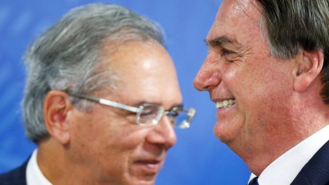 O ministro da Economia, Paulo Guedes, e o presidente Jair Bolsonaro aparecem de perfil sorrindo