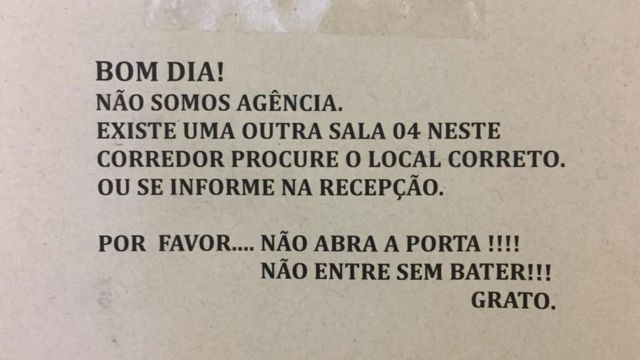 Placa colada em uma porta do Edifício Claudina, na Barão de Itapetininga. Ela diz: "Bom dia! Não Somos agência. Existe outra na sala 04 neste corredor, procure o local correto ou se informe na recepção. Por favor não abra a porta! Não entre sem bater. Grato."