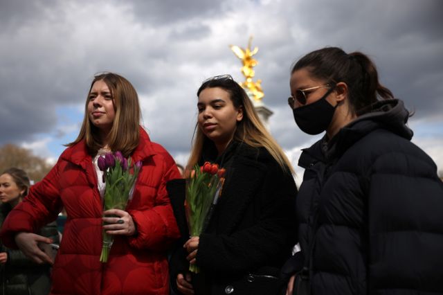 Members of the public hold flowers outside Buckingham Palace