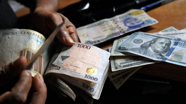 Un homme échange des naira nigérians contre des dollars américains à Lagos, Nigeria - 2021