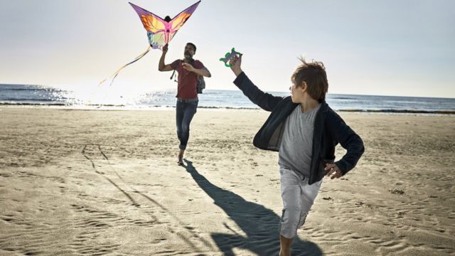 padre e hijo elevan cometa en la playa