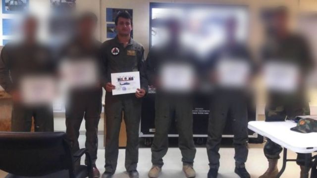 Momand standing with colleagues holding a certificate displaying a helicopter