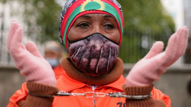 Activists in jumpsuits and handcuffs in prison protest human rights violations against the Oromo people of Ethiopia during a protest across Downing Street in Whitehall in London, England, on 10 October 2020.
