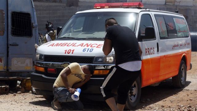 فلسطينيان يبكيان بجوار سيارة إسعاف