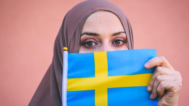 سويدية مسلمة ترفع علم السويد