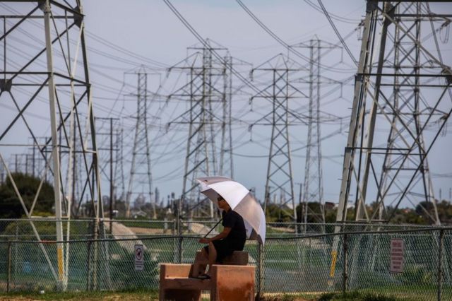 Mujer con paraguas ante los postes eléctricos de Redondo Beach, California.