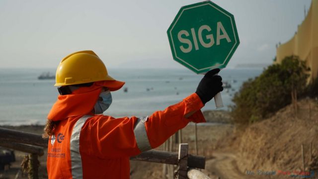 Operrio segura placa em que se l 'siga' no porto de Chancay