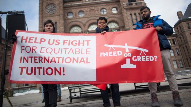 一群在加拿大的国际学生及其支持者手持标语，呼吁人们关注该群体面临的几个问题，包括狭窄且昂贵的住房、高昂的学费、雇主的剥削以及获得永久居留权的艰难途径