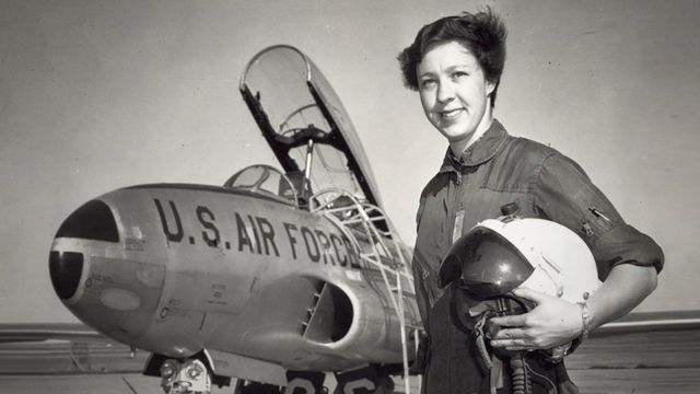 Black and white image of Wally Funk with a US Air Force aircraft behind