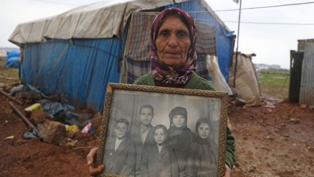 امرأة نازحة من بيتها تحمل صورة لها مع عائلتها وهي طفلة