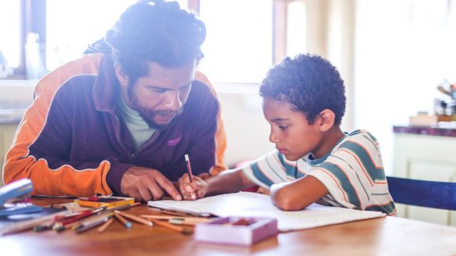 Padre haciendo deberes con su hijo.