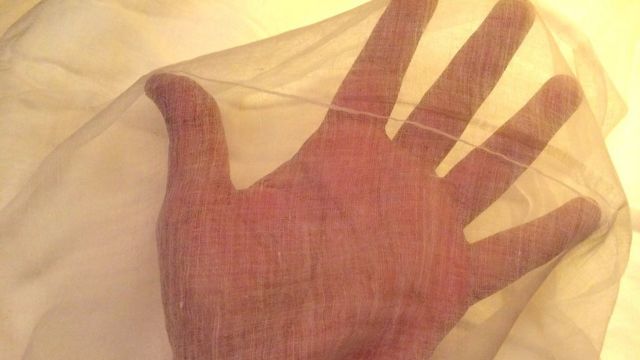 The palm of a hand seen through muslin
