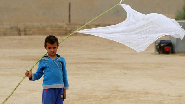 طفل عراقي يلوح بعلم أبيض في محيط الموصل ليعلن أنه مدني وليس مقاتلا.
