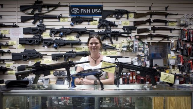 Una comerciante de armas en Texas, frente a un mostrador y una pared con rifles de asalto
