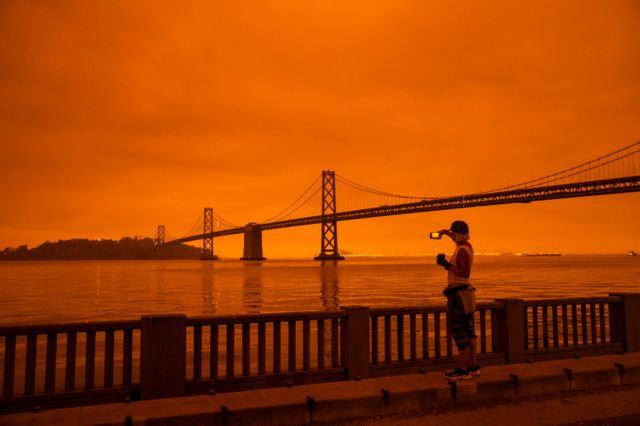 A woman takes in the view from the Embarcadero as smoke from various wildfires blankets San Francisco in darkness and an orange glow on 9 September 2020