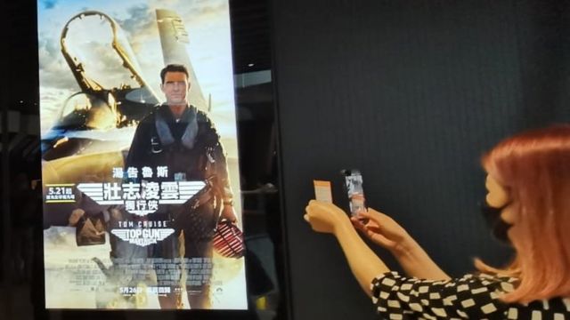 香港一家电影院门口一位女性观众在拍摄《壮志凌云：独行侠》的招贴画。(photo:BBC)