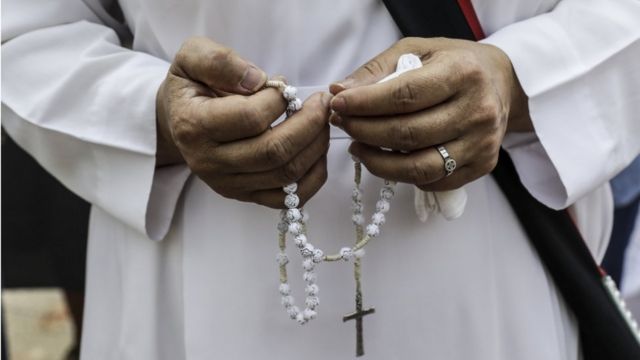 Una persona sosteniendo un rosario.