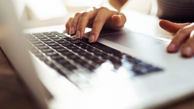 Una mujer tipeando en una computadora