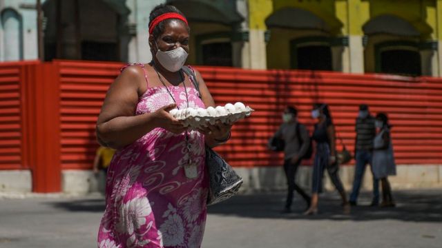 Mujer en Cuba con cartón de huevos.