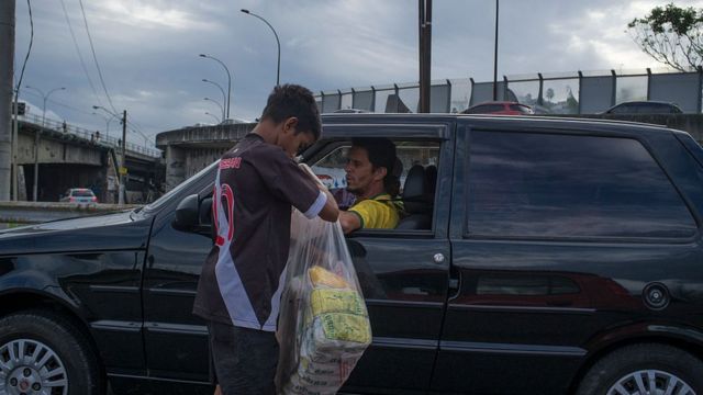 A young man selling cookies to the driver stood on the road