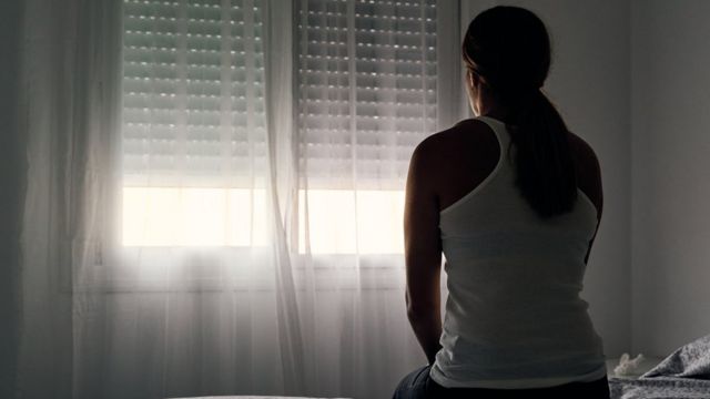 Woman sitting on a bed looking out the window