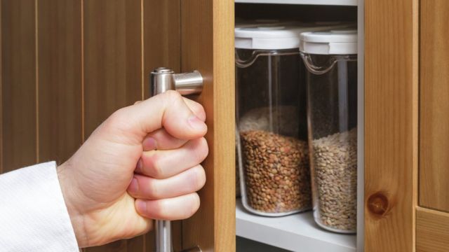 Opening a kitchen cupboard containing storage jars