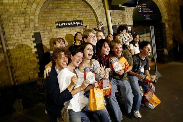 Молодые люди на лондонском вокзале Кингз Кросс у таблички с номером платформы