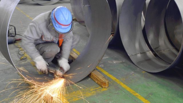 Trabalhador solda a junta de um tubo de aço em uma fábrica em Wuxi, província de Jiangsu, na China