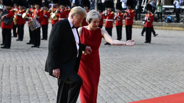 Donald Trump segura a mão de Theresa May para subir escadas