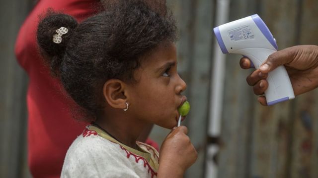 Des agents de vulgarisation sanitaire du ministère de la santé mesurent la tentation d'une jeune fille lors d'un dépistage porte-à-porte pour freiner la propagation du coronavirus COVID-19 à Addis-Abeba, en Éthiopie, le 20 avril 2020