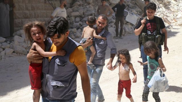 Syrian men carry injured children amid the rubble of destroyed buildings following reported air strikes on the rebel-held neighbourhood of Al-Mashhad in the northern city of Aleppo, on July 25, 2016