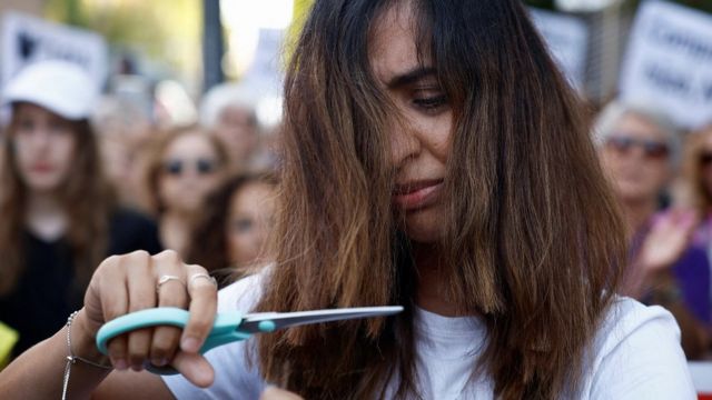 Woman cutting hair outside the Iranian Embassy in Madrid, Spain