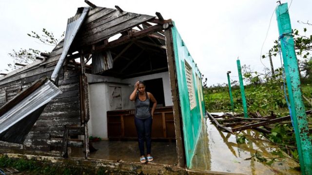 Женщина стоит среди обломков дома на западе Кубы