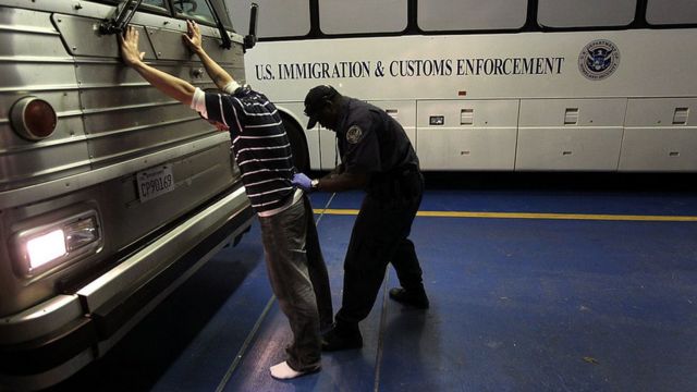 Agente de ICE revisando a un inmigrante indocumentado.