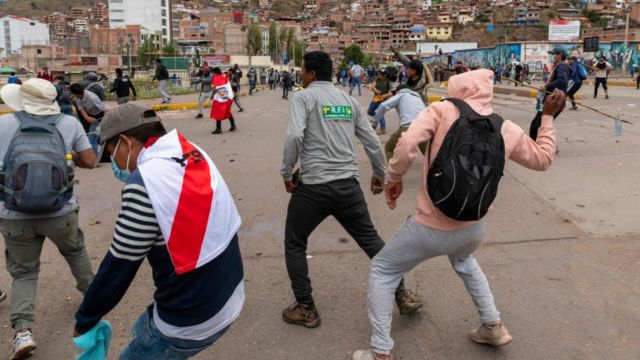 Manifestantes atirando pedras na polícia em Cusco.