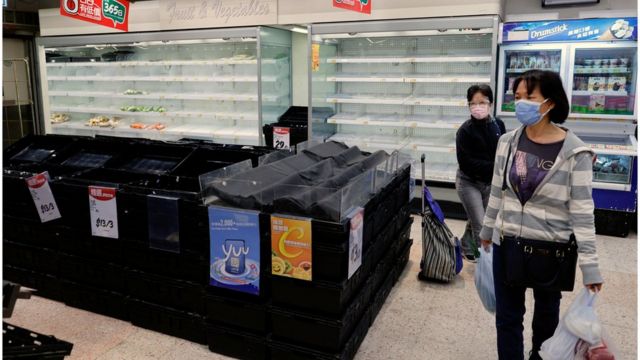 Customers wearing face masks shop in front of partially empty shelves at a supermarket, ahead of mass coronavirus disease (COVID-19) testing, in Hong Kong, China March 4, 2022.