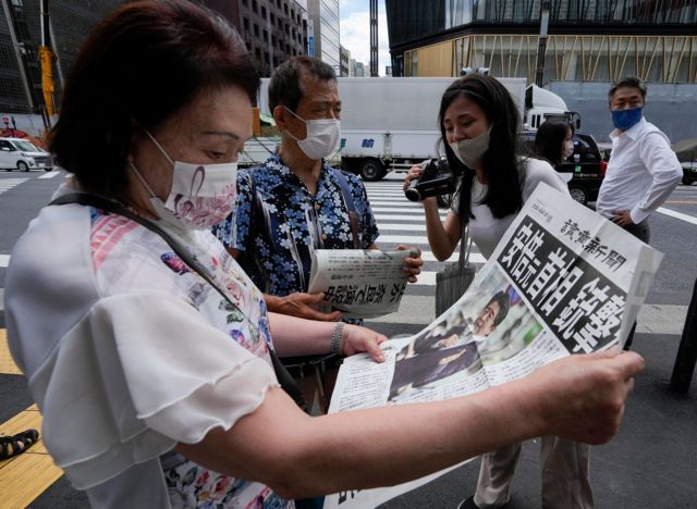2022 年 7 月 8 日、東京の中心部で安倍晋三元首相が射殺されたと報じた新聞を読む女性。
