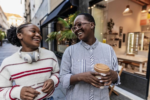 Casal jovem conversando enquato caminha na rua tomando café