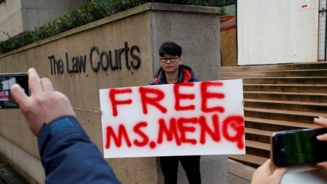 A man holds a sign outside of the B.C. Supreme Court bail hearing of Huawei CFO Meng Wanzhou, who is being held on an extradition warrant in Vancouve