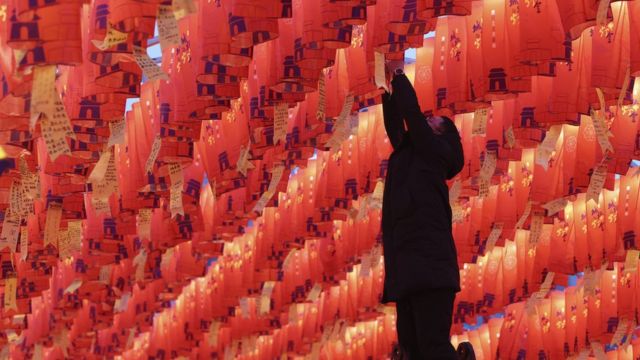 Visitante pendura lanterna de papel vermelho com desejos de Ano Novo durante um show de lanternas na antiga muralha da cidade de Xian, na China