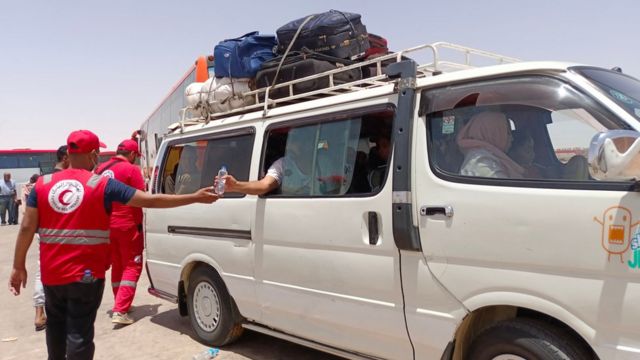 رجال الهلال الأحمر المصري يقدمون الماء للقادمين من السودان