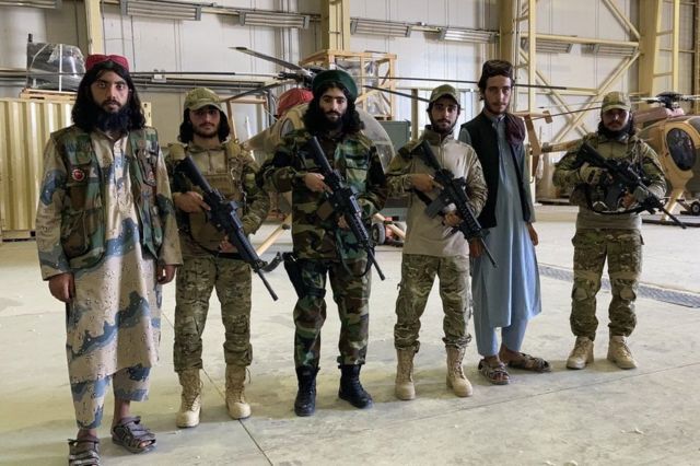 مقاتلو طالبان يقفون أمام مروحيات الجيش السابق في مطار بلخ