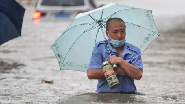 A man wading through flood waters along a street following heavy rains in Zhengzhou
