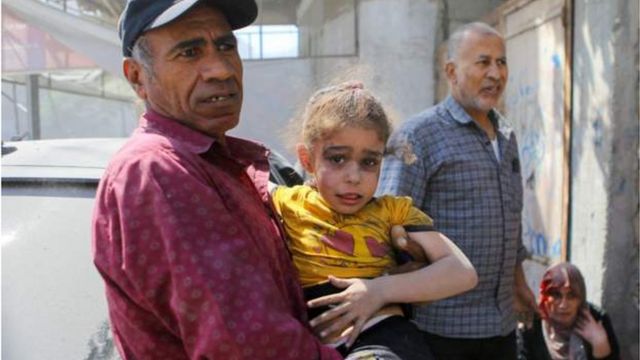 A Palestinian man carries a girl hurt by Israeli strikes in Gaza City