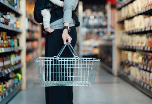 Markette boş alışveriş sepeti tutan bir kadın ve bebeği