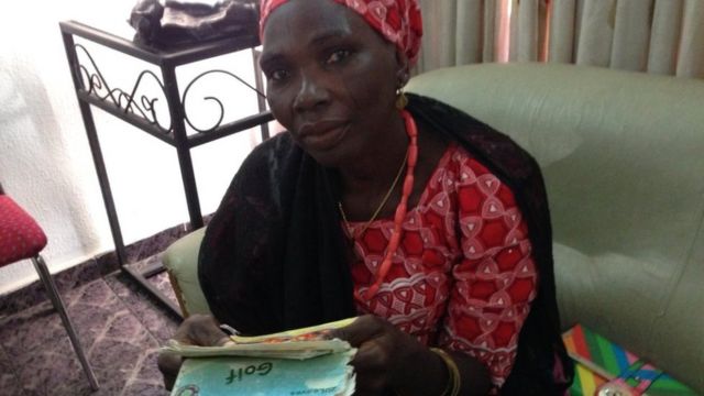 Naomi Adamu's mother Kolo holding one of the notebook diaries