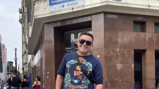 Daniel Araujo posando para a foto e sorrindo em frente a posto de saúde